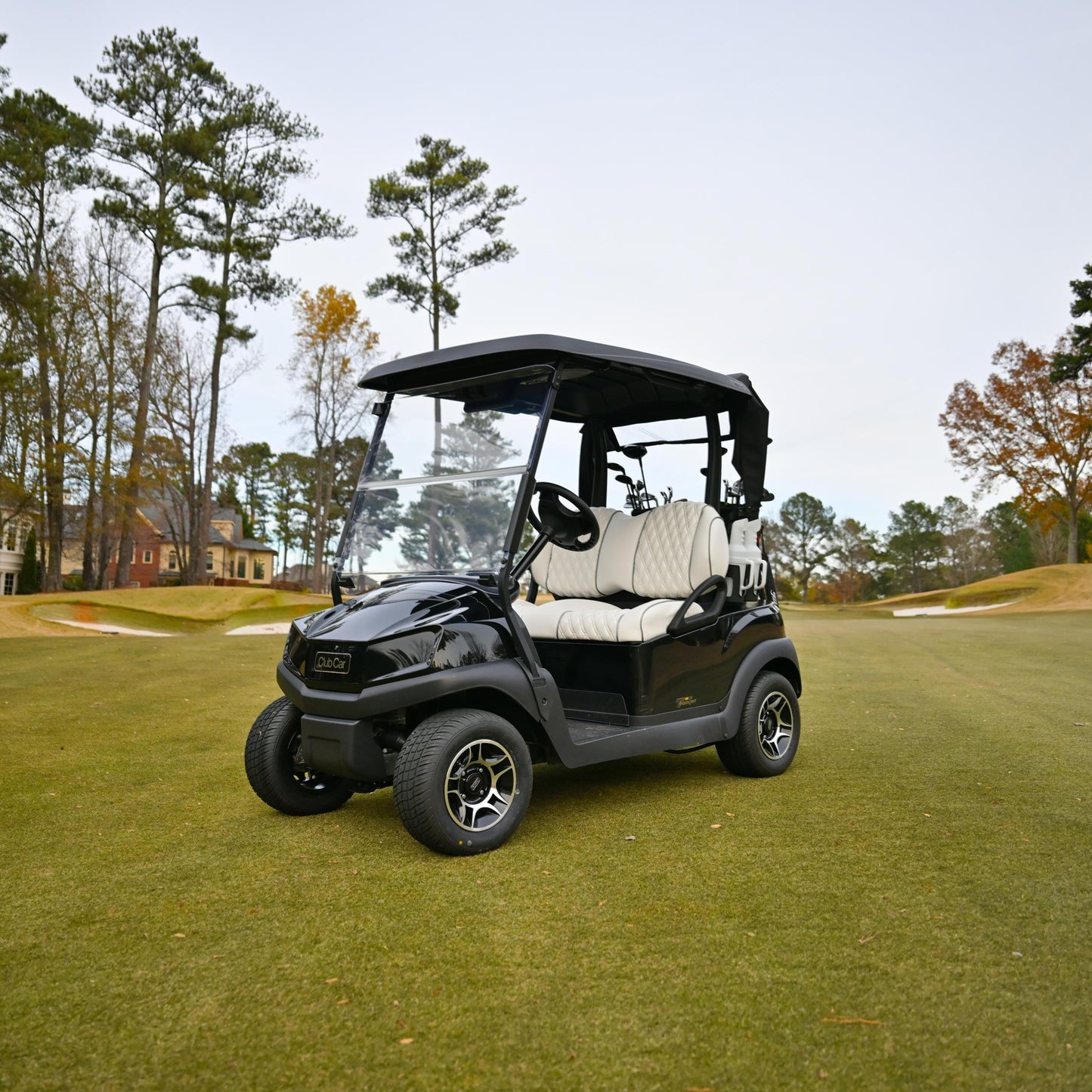 Black Club Car Tempo golf cart on a golf course with trees and houses in the background